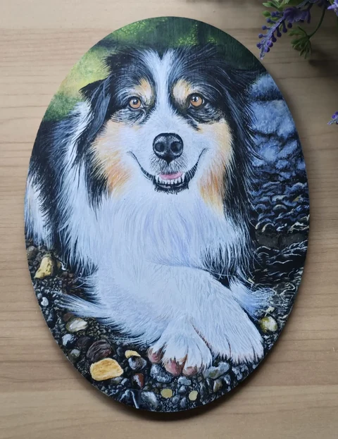 A smiling dog portrait painted on an oval surface